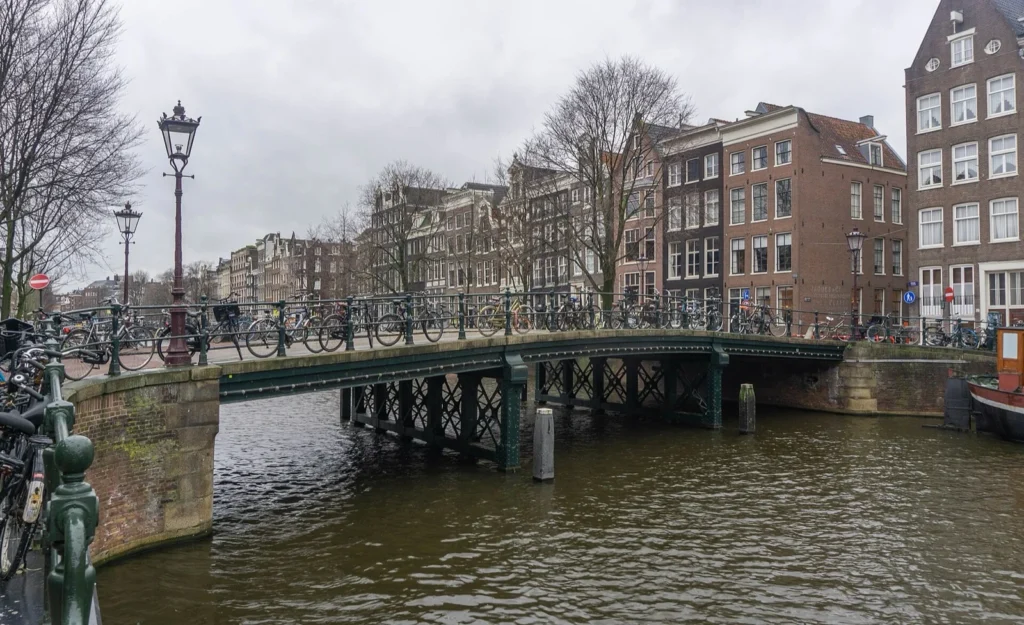 Un ponte su un canale di Amsterdam con molte biciclette parcheggiate lungo il parapetto