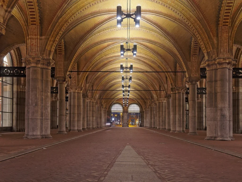 Il passaggio coperto che attraversa il Rijksmuseum, con volte decorate, colonne in pietra e lampade sospese