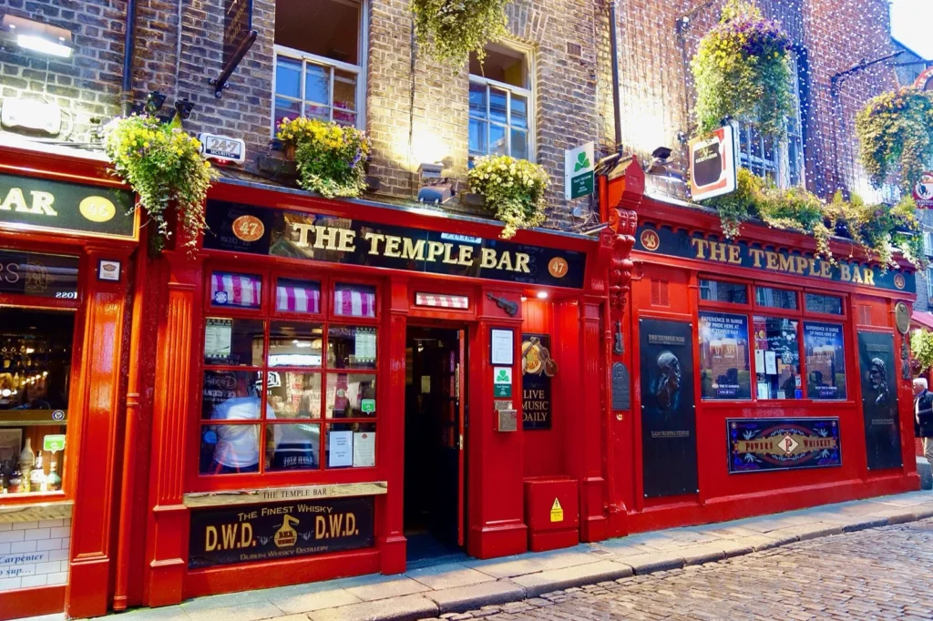 La facciata rossa del pub The Temple Bar nel quartiere di Temple Bar a Dublino, con piante alle finestre e strada acciottolata