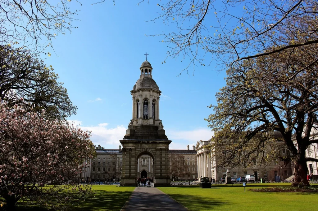 Il Campanile del Trinity College di Dublino in primavera, tra prati, alberi e un albero in fiore
