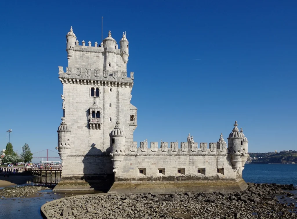 La Torre di Belém, torre fortificata in pietra chiara sulla riva del fiume a Lisbona, sotto un cielo azzurro