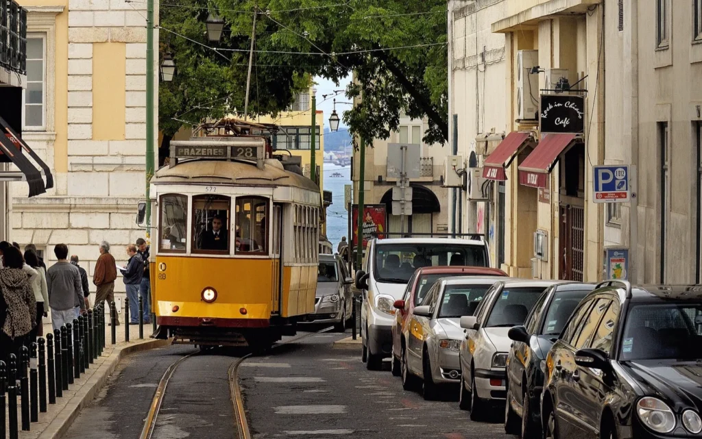Tram giallo della linea 28 per Prazeres in Largo do Picadeiro, nel Chiado, tra palazzi storici e auto parcheggiate