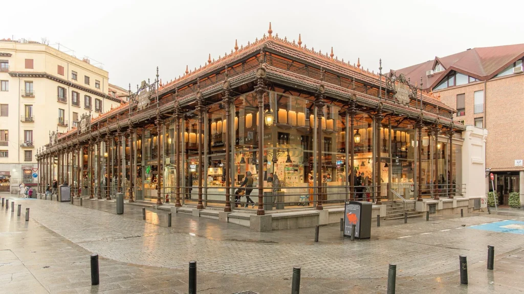 L'esterno del Mercado de San Miguel, con la struttura in ferro e vetro illuminata dall'interno
