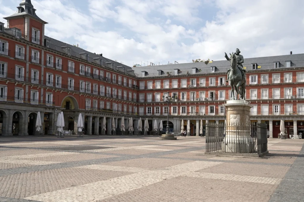 Plaza Mayor quasi deserta, con i portici, le facciate rosse e la statua equestre di Filippo III