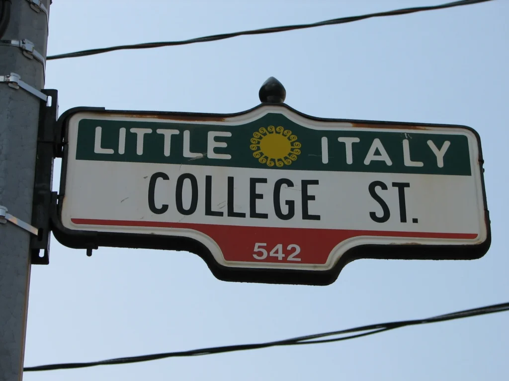 Cartello stradale verde, bianco e rosso con le scritte Little Italy e College St., a Toronto