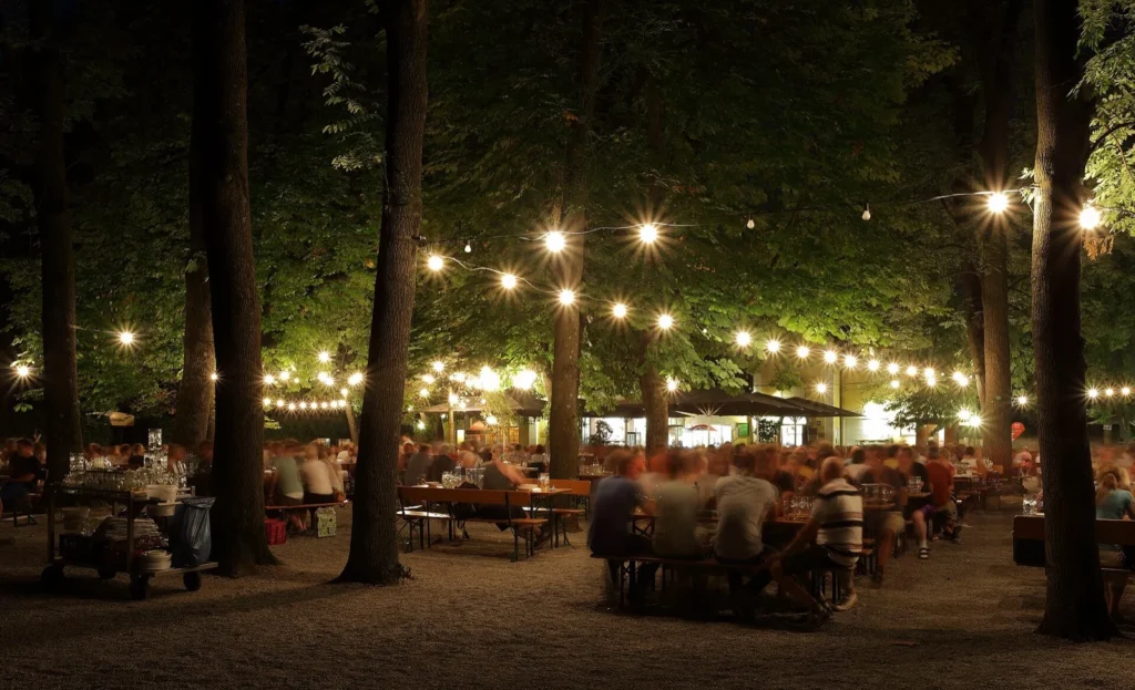 Un Biergarten di sera, con le luci tra gli alberi, a Monaco di Baviera