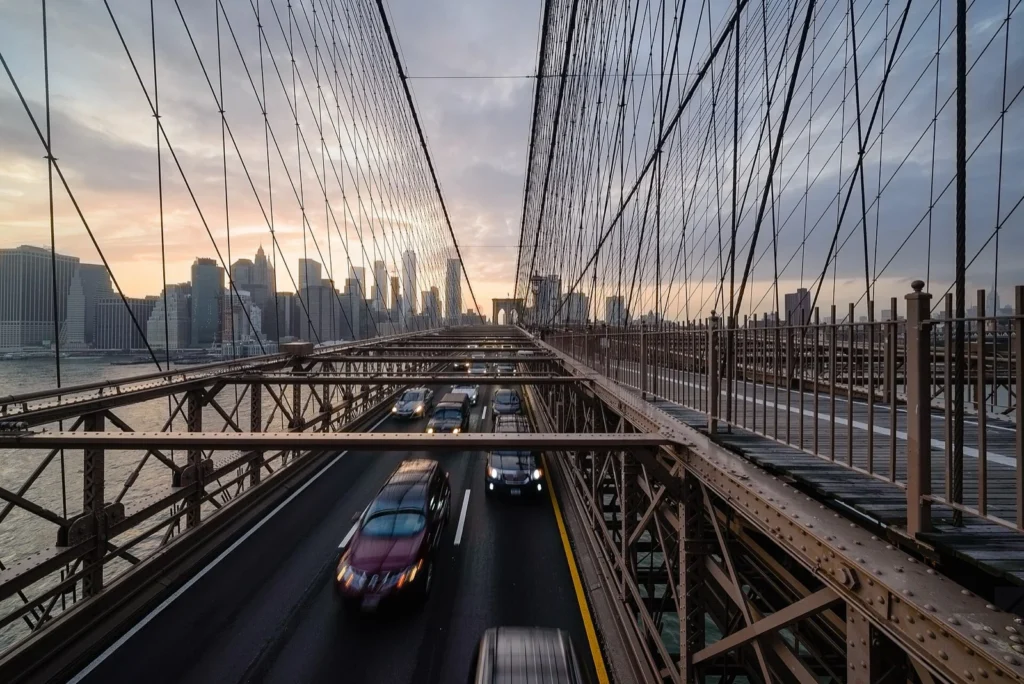 Vista lungo il Ponte di Brooklyn, con i cavi d'acciaio, le auto sulla carreggiata e i grattacieli sullo sfondo